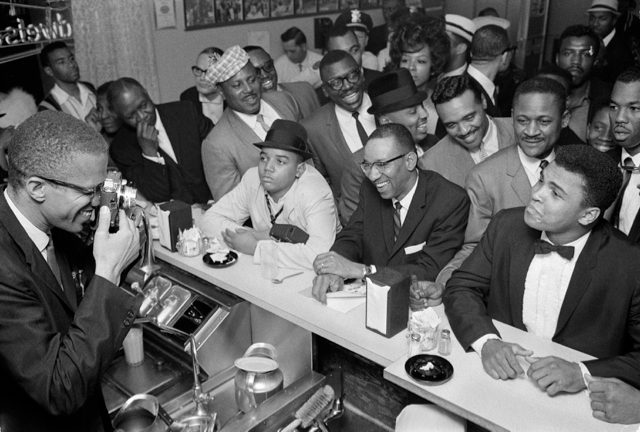Malcolm X photographs Ali in February 1964, after his first defeat of Sonny Liston to become world heavyweight champion. Via Wikipedia.