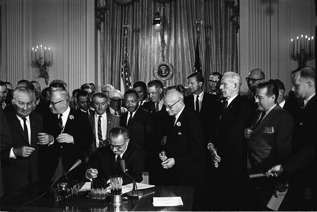 Black and white photograph of President Johnson signing the Civil Rights Act of 1964