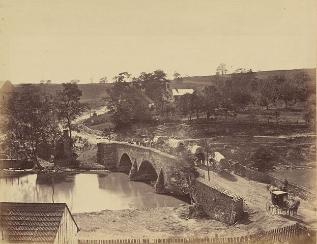 Black and white image of covered wagons crossing the stone bridge at Antietam