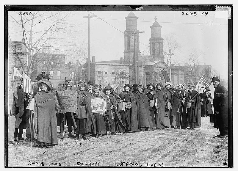 Black and white photograph by Richard Arthur Norton called Suffrage Hikers showing a line of women and men holding protest signs and flags
