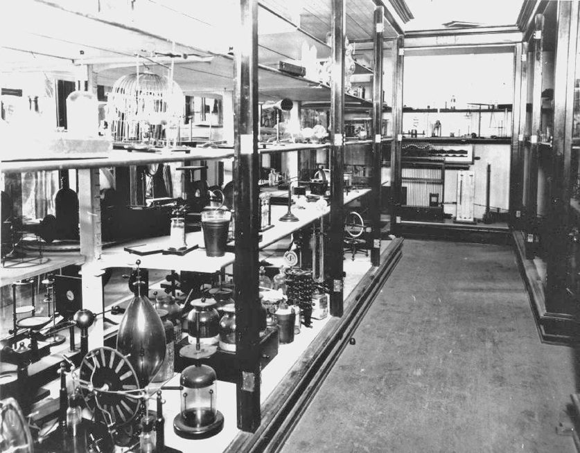 A black and white photograph of the physics department's earliest demo equipment on rows of shelves