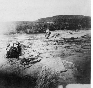 Black and white image of the destroyed Austin Dam with large chunks of debris in the water after the flood of 1900