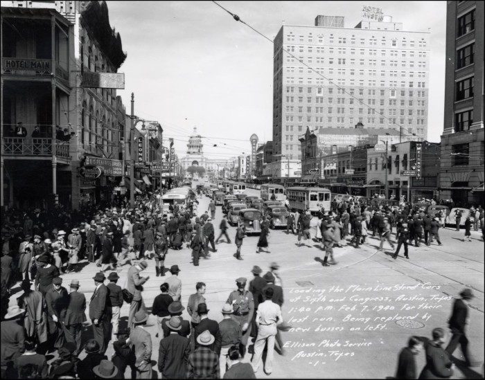 Black and white photograph of large groups of pedestrians crossing Congress Avenue in downtown Austin, Texas