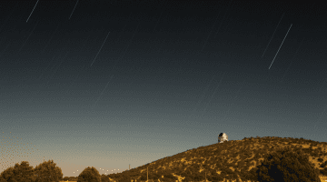 Image of the McDonald Observatory sitting faraway on a shrub covered hill overlooking surrounding grasslands