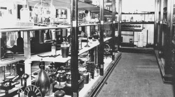 A black and white photograph of the physics department's earliest demo equipment on rows of shelves