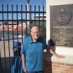 Photograph of Clyde Rabb Littlefield standing next to a plaque memorializing his father