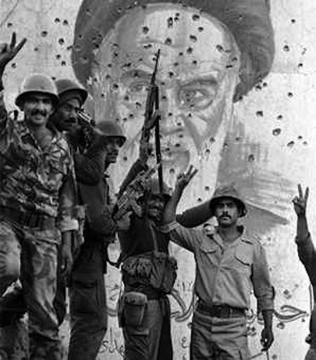 Iraqi soldiers celebrate after recapturing the Faw Peninsula in Iraq during the Iran-Iraq War. Behind them is a bullet-ridden portrait of Iranian leader Ayatollah Ruhollah Khomeini.