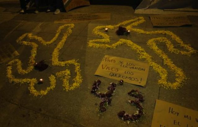 Cempasuchil petals form human-shaped outlines on the ground beside lit candles and a placard during an event held in remembrances of the 43 missing student teachers from the Ayotzinapa. Via REUTERS/Henry Romero