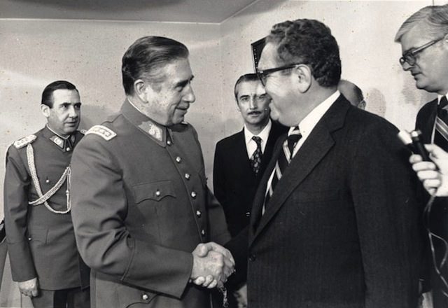 Chilean dictator Augusto Pinochet shaking hands with Kissinger in 1976. Via Wikipedia.