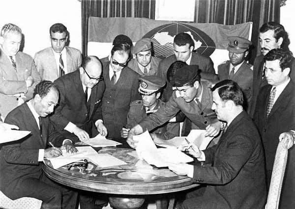 Syria´s President Hafez al-Asad (sitting on the right side) signing the Federation of Arab Republics in Benghazi, Libya, on April 18, 1971 with President Anwar al-Sadat (stting left) of Egypt and Colonel Muammar al-Qaddafi of Libya (sitting in the centre). The agreement never materialized into a federal union between the three Arab states. Photo Credit: The Online Museum of Syrian History via Wikimedia Commons.