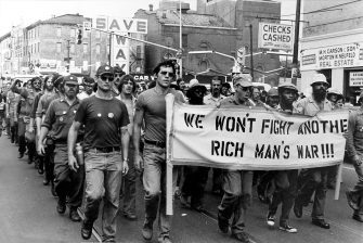 Veterans protest and carry a sign that reads "We won't fight another rich man's war"