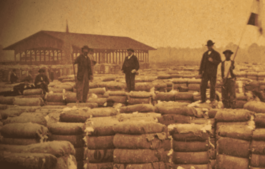 Dock workers in Savannah, Georgia stand on tall mounds of packaged goods.