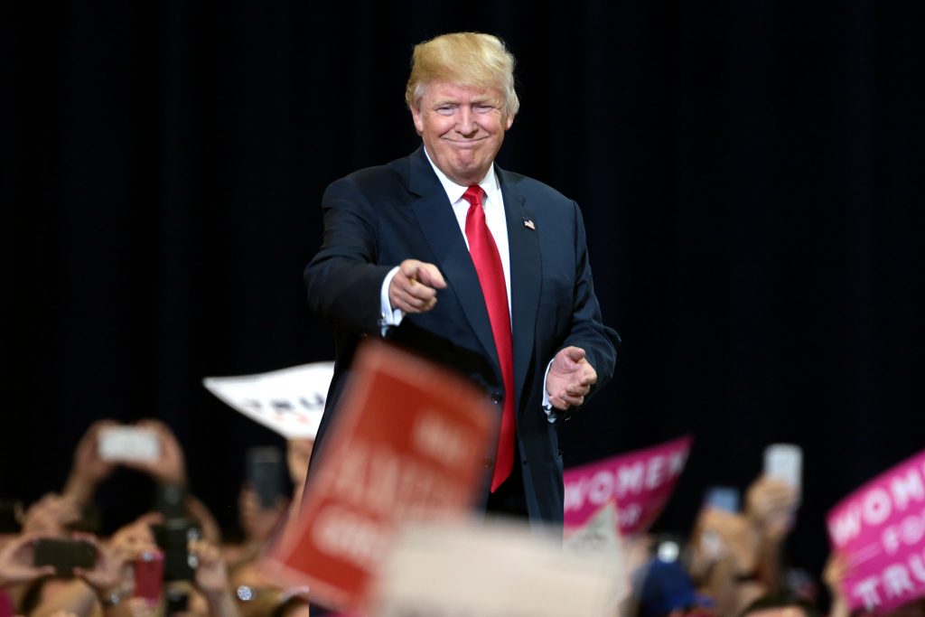 Donald Trump grins and points to supporters at a rally