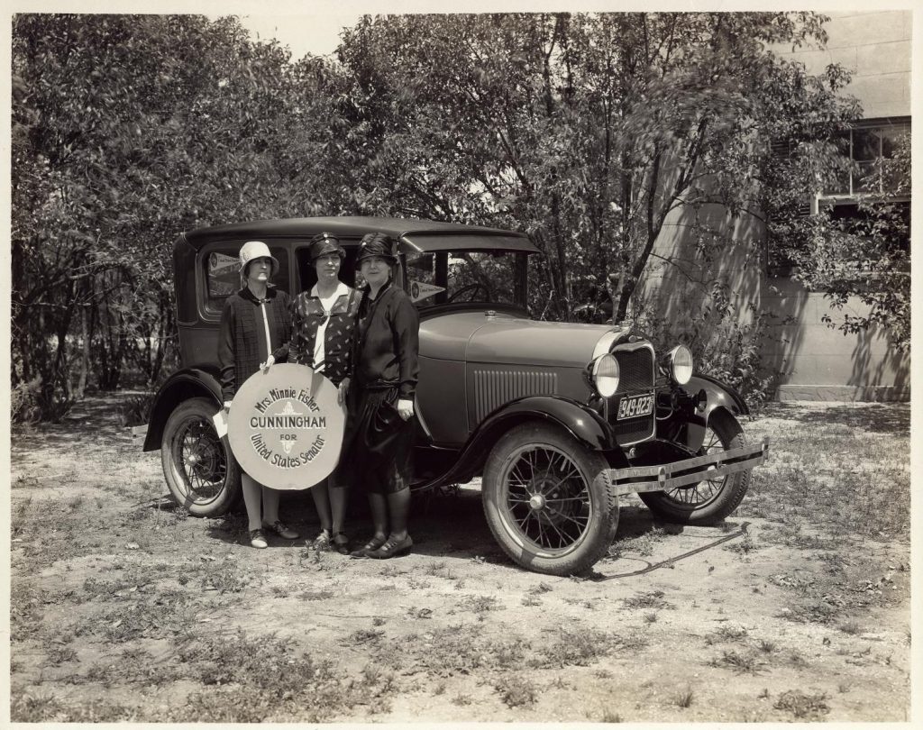 Minnie Fisher Cunningham (far right) and two other women in front of car holding sign that reads: "Mrs. Minnie Fisher Cunningham for United States Senator." Photo Courtesy of the Austin History Center