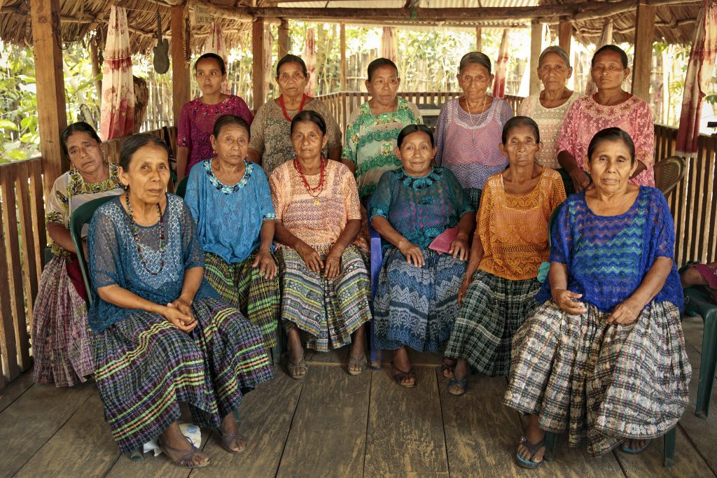 The abuelas [grandmothers] of Sepur Zarco. First row seated (from right-left): Antonia Choc (blue huipil); Felisa Cuc (orange huipil); Rosario Xo (blue huipil); Candelaria Maaz (pink huipil); Manuela Bá (light blue huipil); Demesia Yat (dark blue huipil);

 

Seated behind Demesia Yat (left) (wearing white huipil with green embroidery): Margarita Chub.

 

Standing, second row, (from right-left): Matilde Sub (pink); Catarina Caal (off-white); María Bá (purple huipil); Cecelia Xo (purple huipil); Carmen Xol (tan flowered huipil)