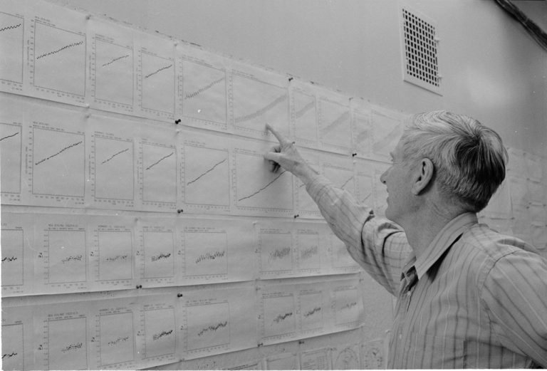 Charles Keeling faces a wall with copies of the Keeling Curve