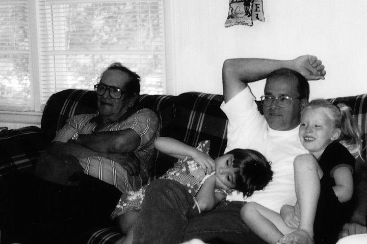 Four people sit on a couch looking toward something off camera. 