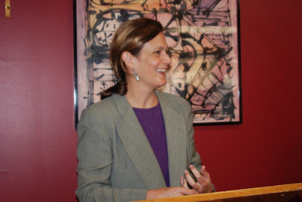 A smiling Erika Pani, photographed while speaking at a lecturn.
