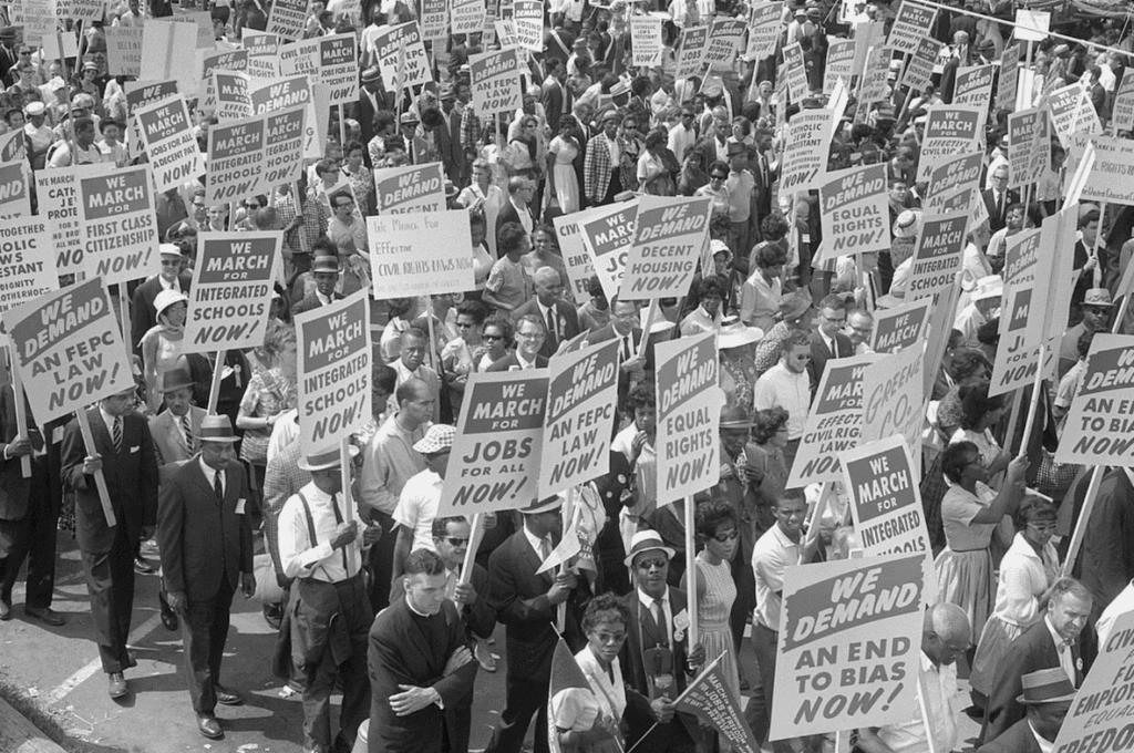 Demonstrators marching in the street holding signs during the March on Washington, 1963. 