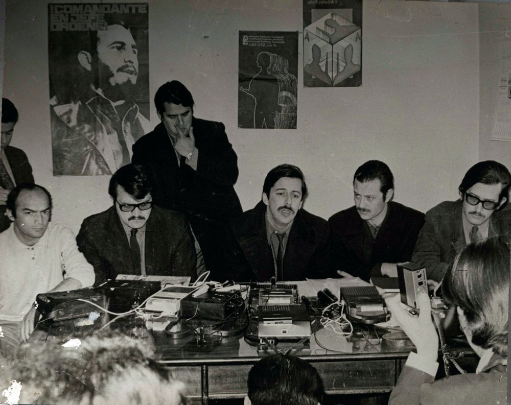 Photograph of members of the Central Committee of the Revolutionary Left Movement (MIR) during a press conference. From left to right are Roberto Moreno, Luciano Cruz, Nelson Gutiérrez, Miguel Enríquez, Bautista Van Schouwen and Andrés Pascal.