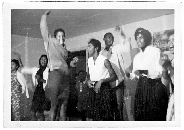 Group of young people standing, some are cheering. 