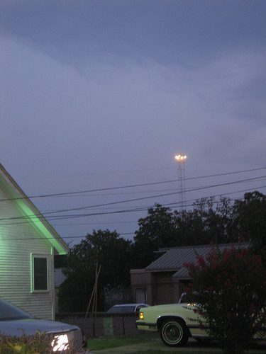 Picture of a modern moonlight tower protruding above the treeline in a residential neighborhood in Austin, Texas
