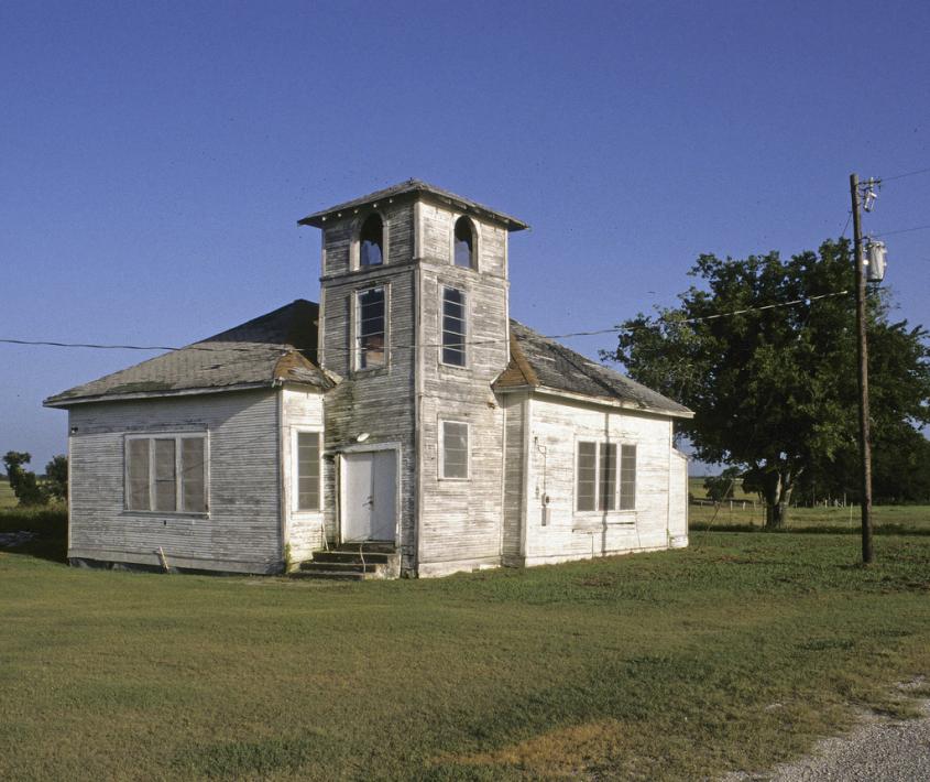 Image of an old, dilapidated white church in a country setting