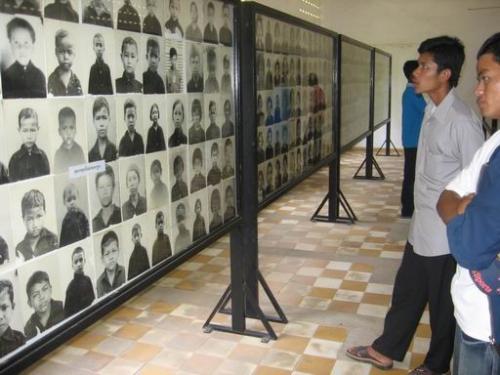Two men look on at museum photos of Khmer Rouge victims
